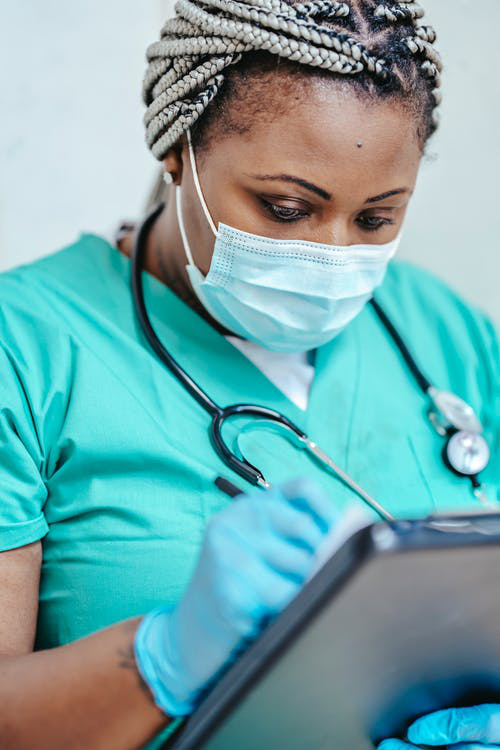 Medical professional in scrubs taking notes