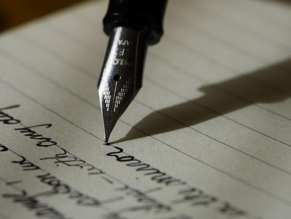 A person writing with an ink pen on a paper