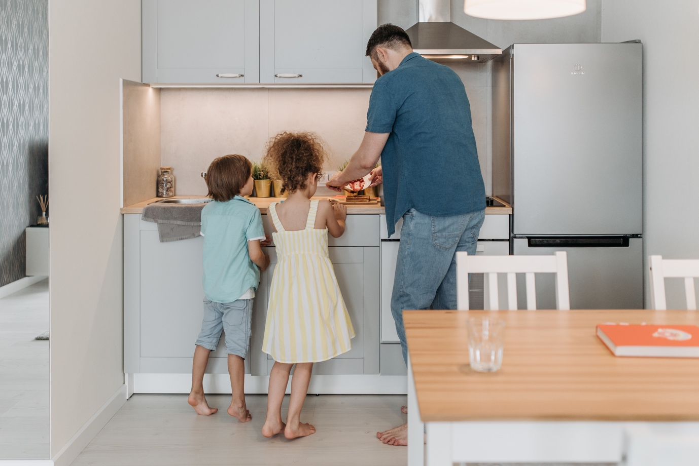 Nanda & Associate Lawyers Canada - A father cooking in the kitchen with his young son and daughter