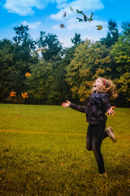  girl in black jacket standing on green grass during daytime