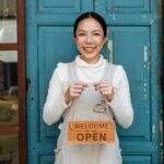 Nanda & Associate Lawyers Canada - small business owner holding an open sign for her business