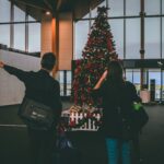 Nanda & Associate Lawyers Canada - Two people standing in front of a Christmas tree at an airport