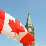Nanda & Associate Lawyers Canada - Canada’s flag in front of a clock tower.